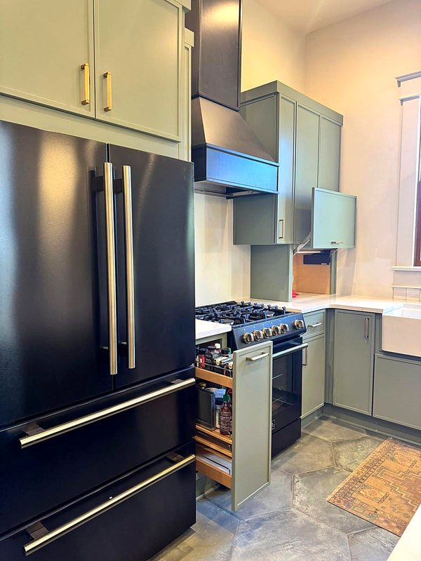 Sage/olive green kitchen with brass pulls, matching green custom range hood with black — kitchen by MNK Cabinet in metro Atlanta