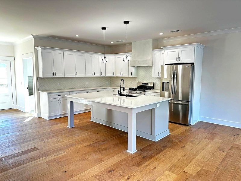White shaker perimeter cabinets with black hardware, oversized light-gray table-leg — kitchen by MNK Cabinet in metro Atlanta